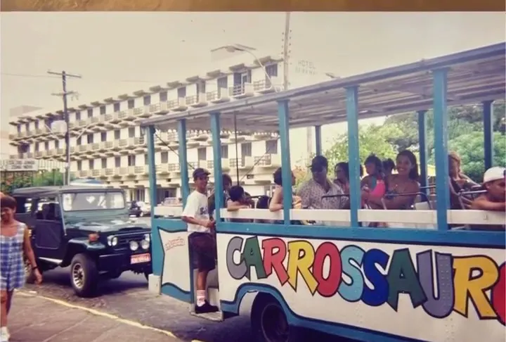 Carrossauro antigo, com o letreiro colorido e o vagão cheio de passageiros.